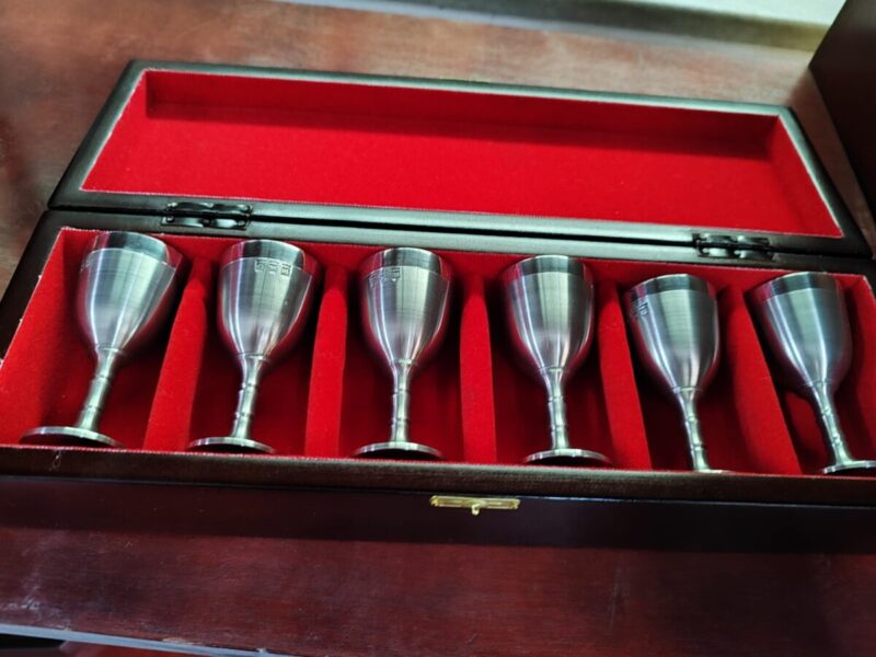 Conjunto de 6 taças para licor em estanho dentro de um estojo de madeira forrada de veludo.